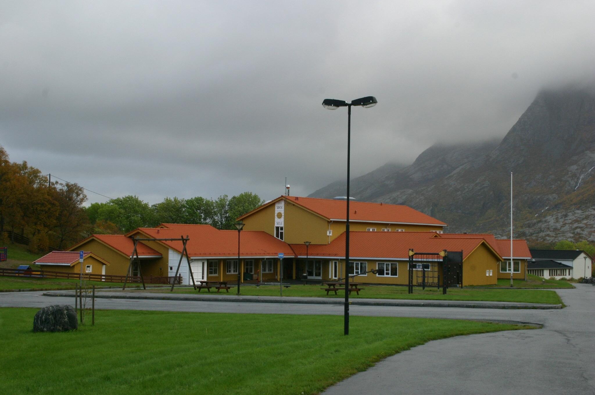 Sommerbilde av skolen overskyet fra s&oslash;r