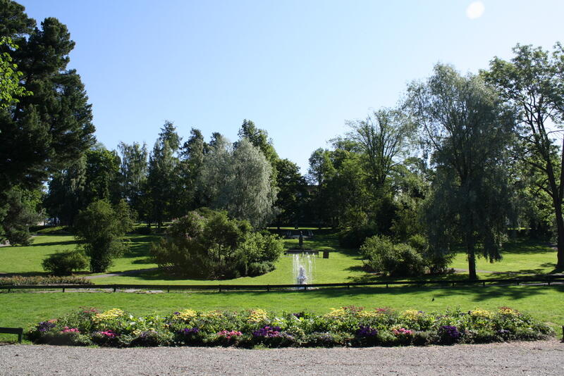 Park med fontene og frodige busker og trær