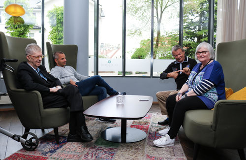 Tre FNDB-medlemmer (to menn og en kvinne), sitter sammen rundt et bord med en mannlig tolk-ledsager.