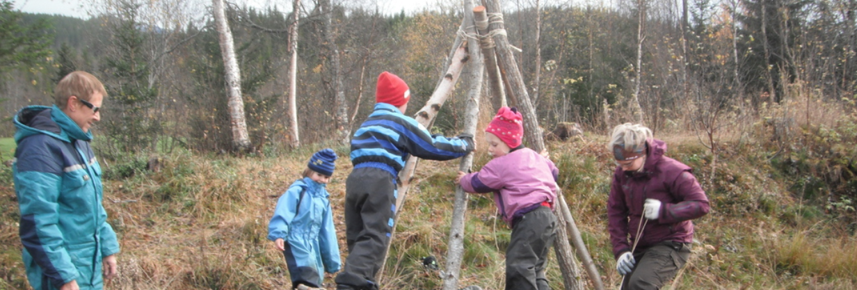 Bilde av barn og voksne som leker i skogen