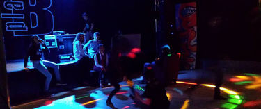 Salen og scenen på Plan B, med scenen belyst og en gruppe ungdommer ved scenekanten
