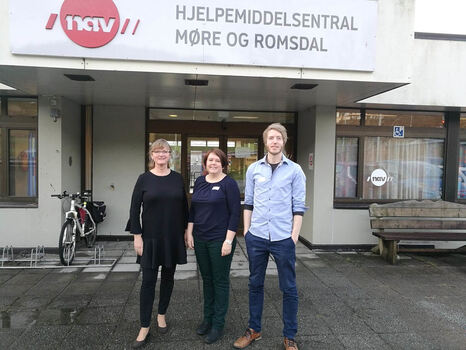 To kvinner og en mann står foran inngang og skiltet til NAV hjelpemiddelsentral Møre og Romsdal i Ålesund.