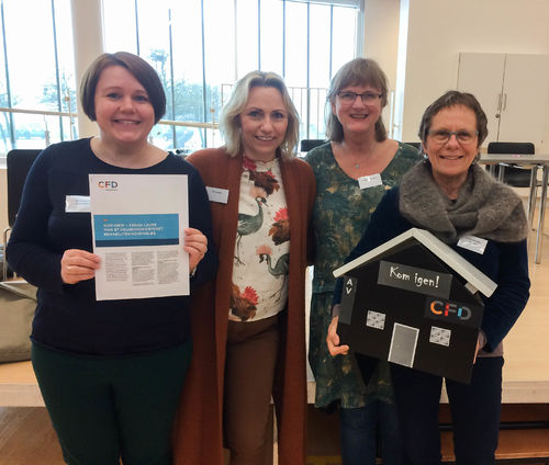 Fra venstre Elin Haugland, Siw Knutstad, Inger Marie Storaas og Gunilla H. Rønnblom. Fire kvinner står tett samme og smiler. Hun ytterst til venstre holder på et ark med informasjon om CFD, men hun som står ytterst til høyre viser fram et "CDF-hus" med påskriften "Kom igjen!".