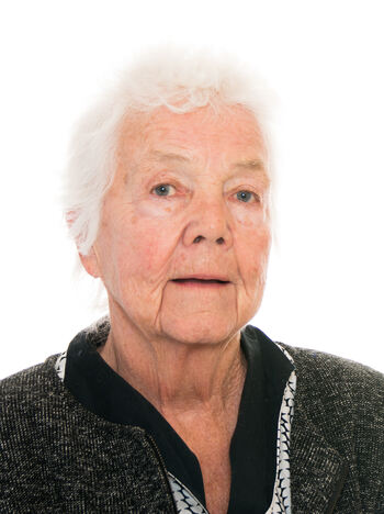 Portrettfoto av eldre kvinne. Hvitt, kort hår. Mørk jakke, med lysere skjorte under.