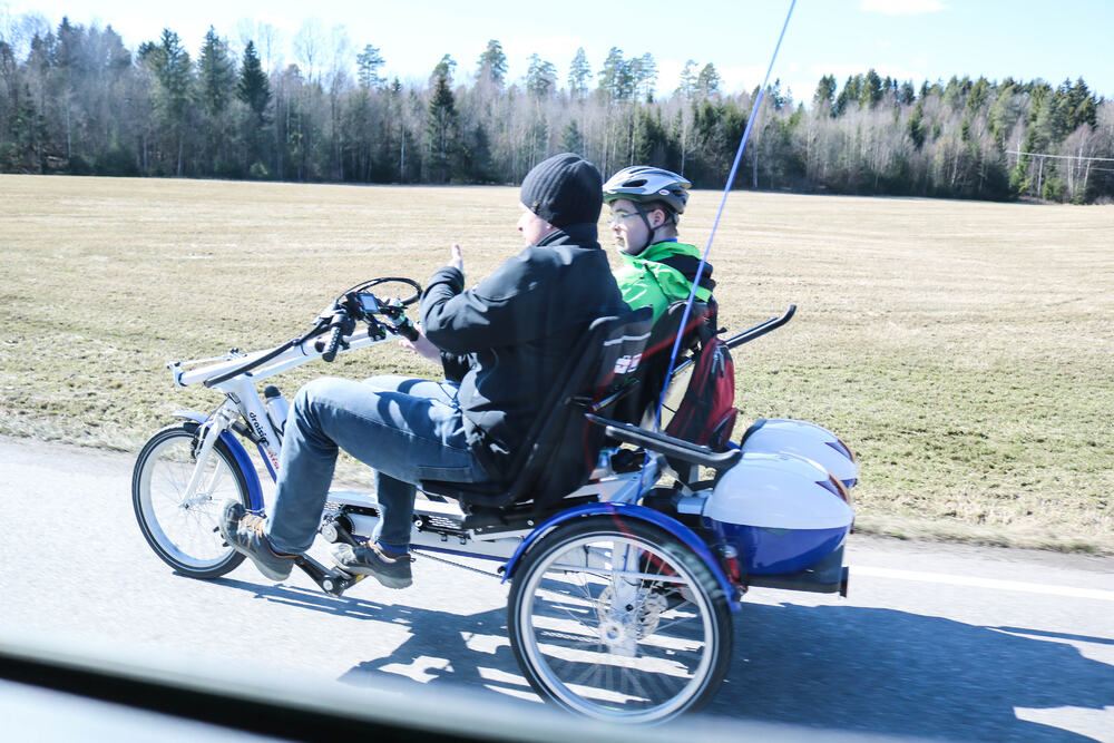 To personer sykler på en horisontandelt tandemsykkel i landlige omgivelser.