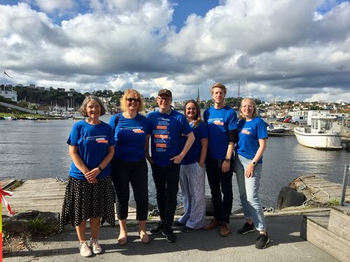 NKDBs informasjonsarbeidsgruppe under Arendalsuka: Nina Sellæg (Statped), Trine Seljeseth (koordineringsenheten), Roy-Morten Østerbøl (koordineringsenheten), Rolf Mjønes (Eikholt) og Stine R. Winciansen (Statped). Foto av Roy-M. Østerbøl. Seks personer, to menn og fire kvinner, stående på en fergekai.