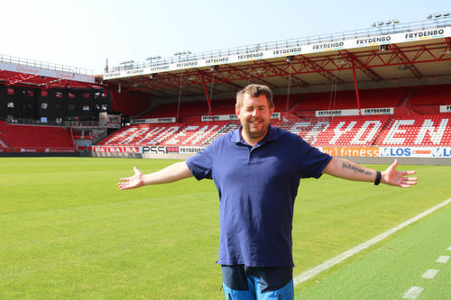 Christian Jensen inne på flotte Brann stadion. Foto: Roy-Morten Østerbøl. Mann i blå piquet poserer inne på Brann stadion i Bergen.