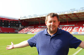 Roy-Morten Østerbøl Mann i blå piquet poserer inne på Brann stadion i Bergen.
