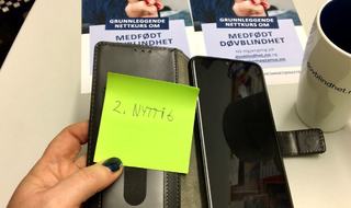 Illustrasjonsbilde. Grønn post-it-lapp, hvor det står nyttig, ligger inni etuiet til en smarttelefon.