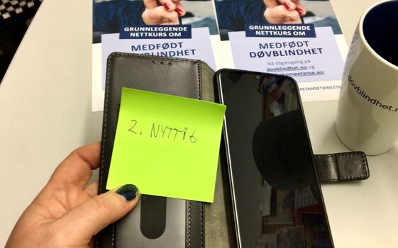 Grønn post-it-lapp, hvor det står nyttig, ligger inni etuiet til en smarttelefon.