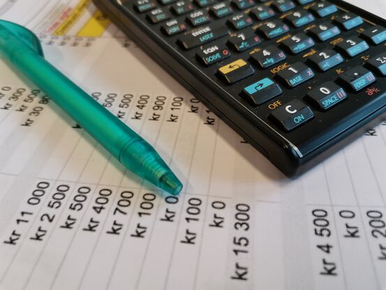 Et ark med budsjett. En penn og en kalkulator ligger oppå.