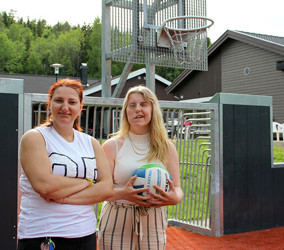 To kvinner under basketball-kurv på universelt utformet ballbinge. 