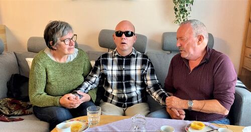 Eskil Nordheim sammen med sine foreldre Lillian og Gunvald Nordheim. Foto: Roy-Morten Østerbøl. Døvblind mann sammen med sine foreldre i en sofa, far til høyre og mor til venstre.