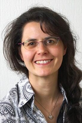 Privat Portettfoto av kvinne med briller og brunt, langt bølgete hår.