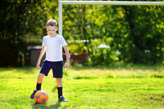 17162881-little-boy-playing-a-soccer-game-on-summer-day