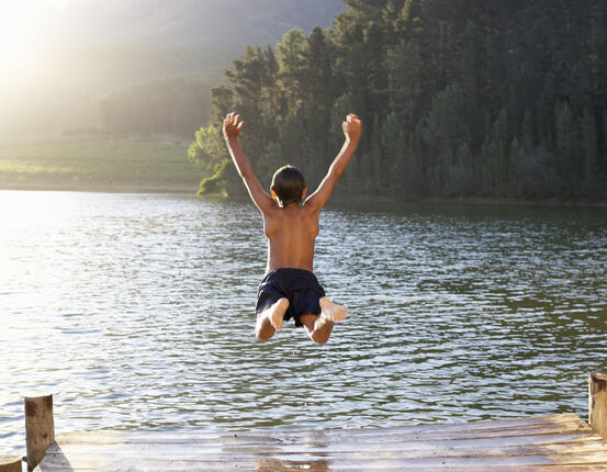 Illustrasjonsbildet viser en ung gutt som hopper i en innsjø iført badetøy.