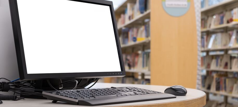 Computer with blank screen monitor on table in interior library