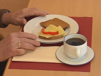 Kaffekopp, serviett og to brødskiver på en hvit tallerken, med en rød brikke under.