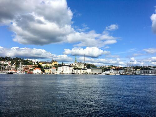 Arendal sentrum, sett fra sjøsiden. Foto av Roy-M. Østerbøl. Norsk by sett fra sjøsiden, blå himmel og tykke gråhvite skyer over byen som ligger på Sørlandet.