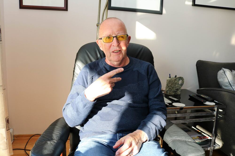 Eldre døvblind mann med filterbriller sitter i sin stressless og kommuniserer med tegnspråk.