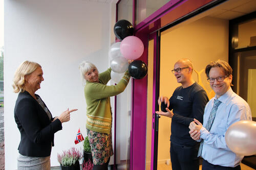 Åpningsforberedelser: Leder for kurs- og utviklingsavdelingen Cecilie Horgen i samtale med tegnspråkkonsulentene Robert Macha og Martin Skinnes. Torunn Müller-Nilssen fikser ballongene før gjestene kommer. Foto: Anette Sæstad. To kvinner og to menn forbereder åpning av nytt kurssenter med flagg og ballonger ved inngang.