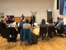 Statped En gruppe folk sitter rundt en sirkel med møtebord, fremst står to kvinnelige forelsere.