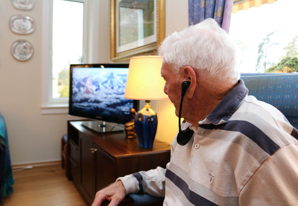 Eldre mann ser på tv med taleforsterker.