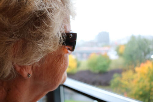 Kvinne ser ut av vindu med oransje filterbriller.