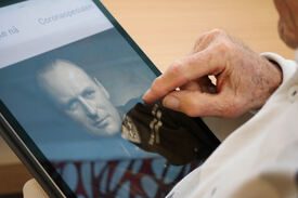 Eldre mann ser på et bilde av kong Olav på sin iPad.