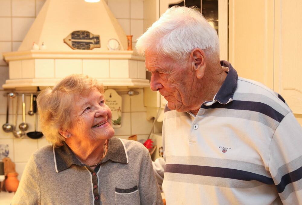 eldre ektepar på kjøkken som ser kjærlig på hverandre