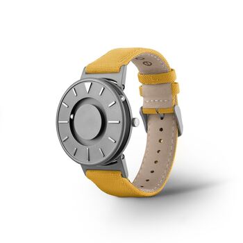 Armbåndsur med gul rem, der viserne består av kuler og magneter.