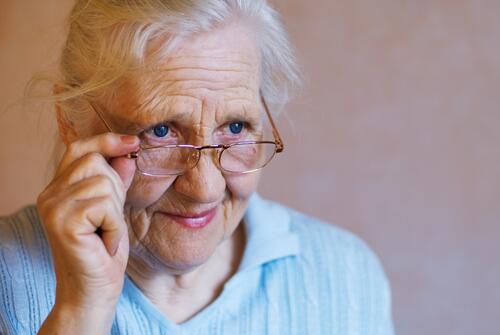Eldre kvinne kikker over brilleglasset.