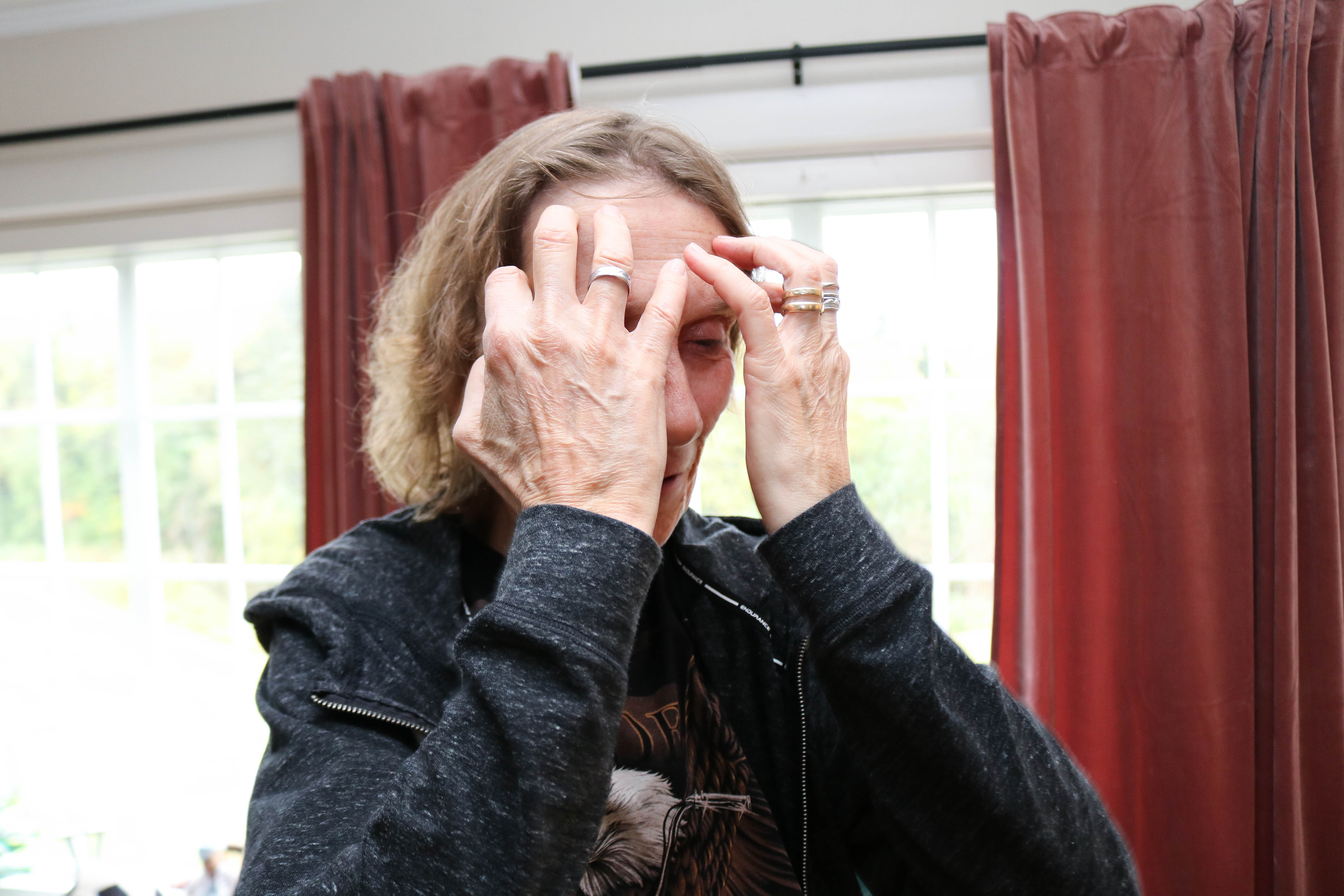 Døvblind kvinne holder hendene foran ansiktet, hun er alvorlig. 