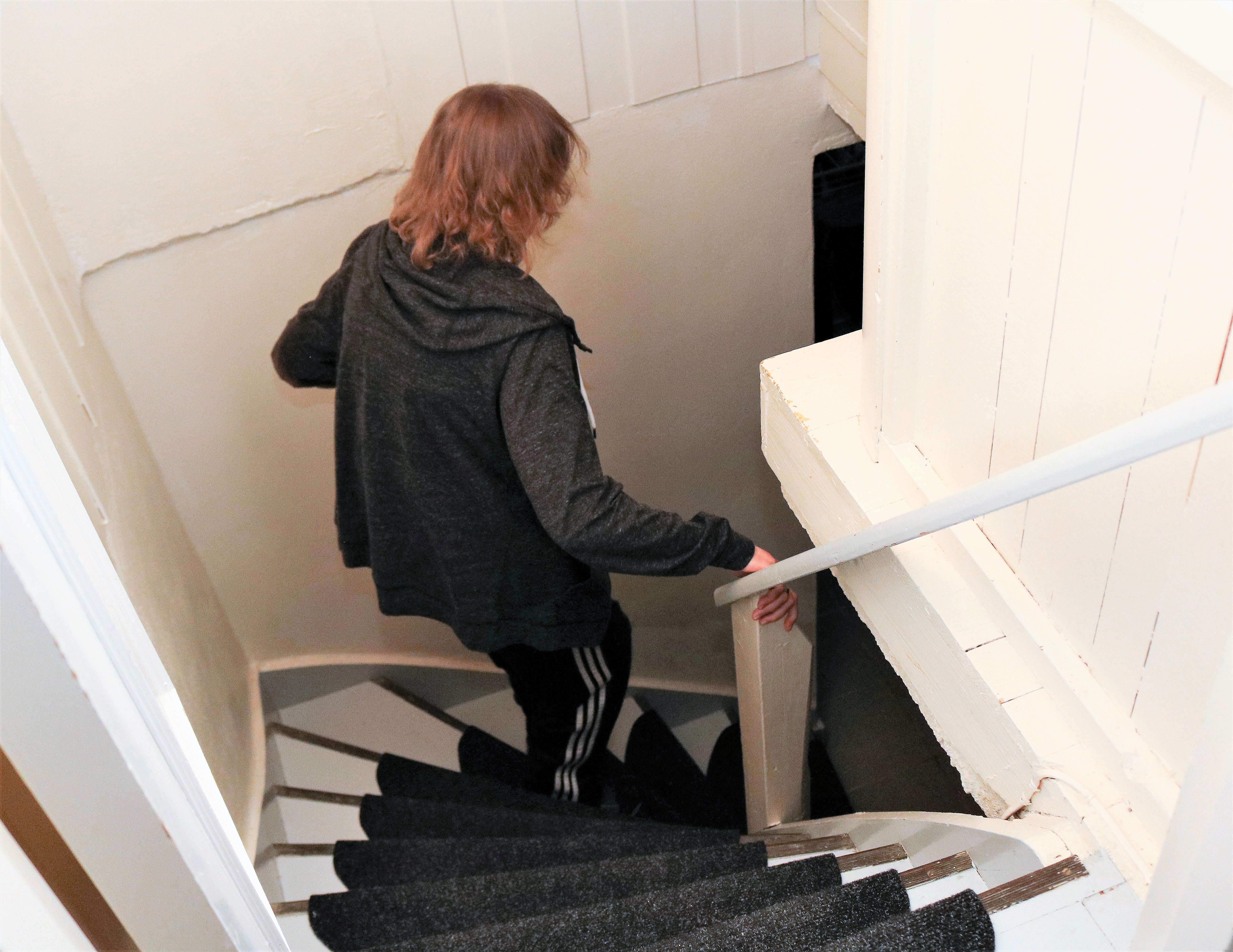 Døvblind kvinne går ned en trappegang til kjeller. 