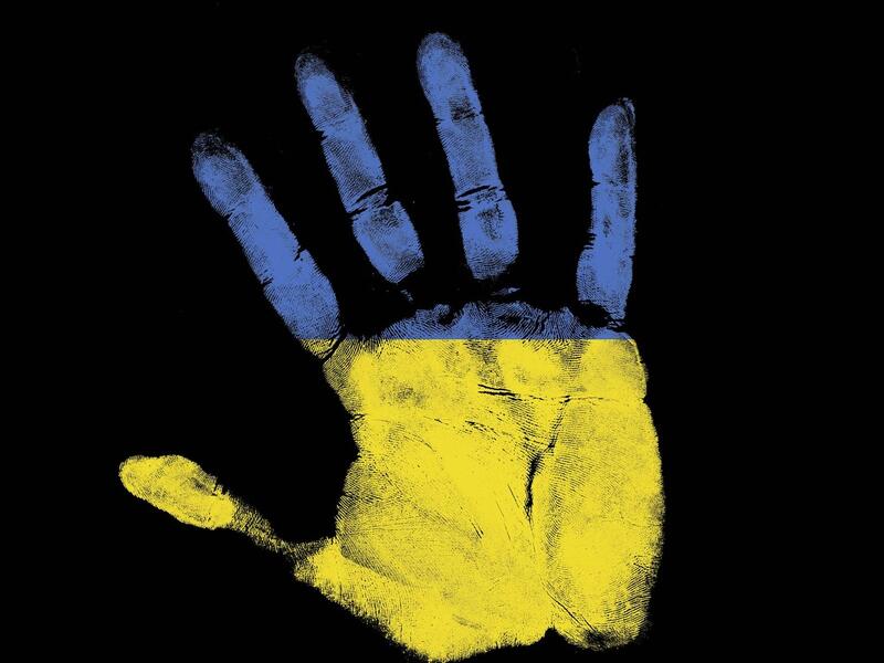 Håndflate malt i halvt blått, halvt gult. Svart bakgrunn.