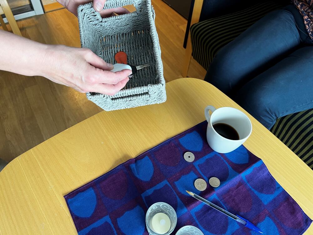 Et bord med en kaffekopp, ting som lå på bordet samles i en kurv