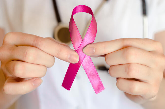 29078093-woman-doctor-keeps-a-pink-ribbon-close-up-breast-cancer