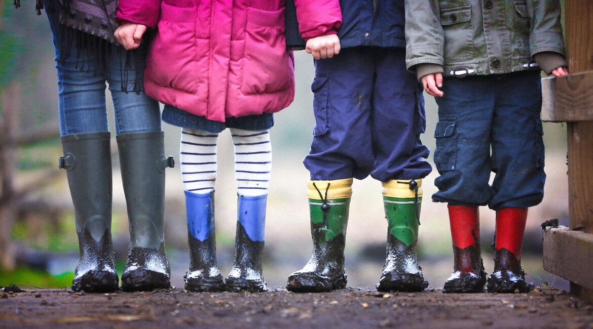 Four children pictured from the waist down in their rainboots