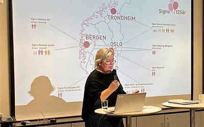 Kvinne foreleser med powerpoint-slide med kart over Sør-Norge bak seg.