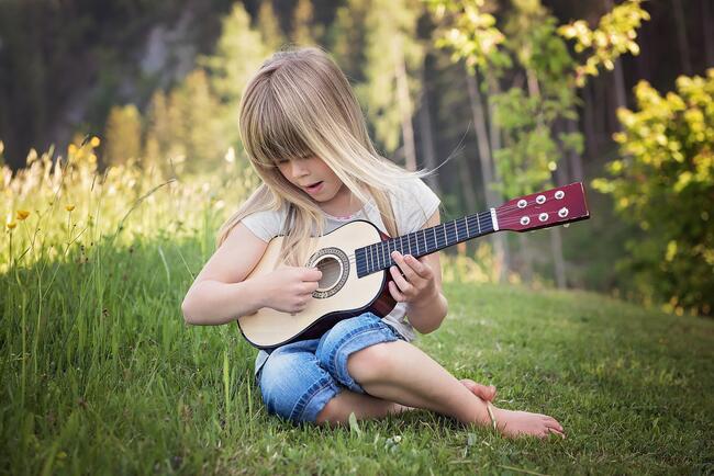 Jente som spelar gitar. Illustrasjonsfoto