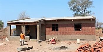Bygning under oppføring i det sørøst-afrikanske landet Malawi. Man i oransje t-skjorte går foran bygningen.
