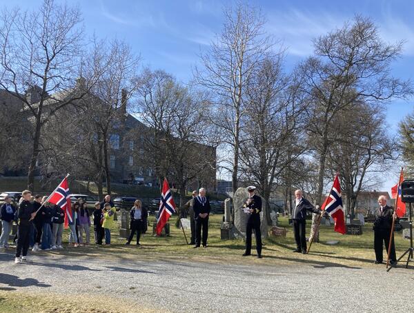 forsamling under minnemarkering for frigjørings- og veterandagen, med norske flagg