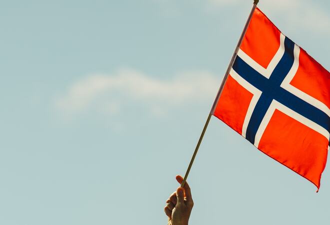 32622307-hand-holds-norwegian-flag-against-sky