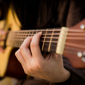 Nærbilde av hender som spiller gitar