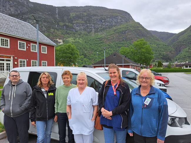 GODT SAMARBEID: Frivillig sjåfør Linda Skjoldal (f.h), helsefagarbeidar Hilde Hokstad, leiar ved kjøkenet på LBO, Monica Lien, leiar for frivilligsentralen, Anne Kristin Evensen, Ann Kristin Mo – som styrer bodbiltenesta – og medhjelpar Ole Stian Aspevik framfor ein av bilane til heimesjukepleia.