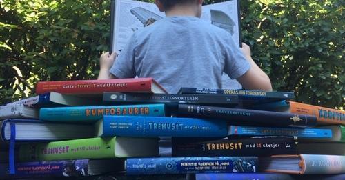 Bøker i stabel, et barn som sitter og leser med ryggen til