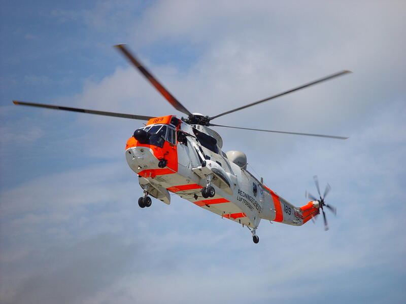 Hvitt og oransje helikopter mot en blå himmel