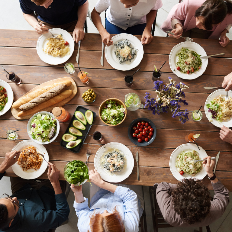 Foto av et spisebord med mange matretter på og mennesker rundt bordet