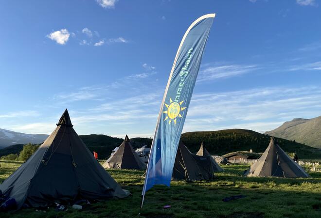 Foto: SommerSkaun/Hanne Olden Banner med tekst foran flere lavvoer på fjellet