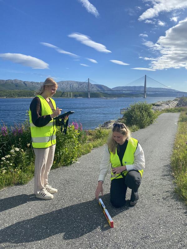 Eline Lie og Lena Lie Andersen måler tverrfall og helningsgrad på adkomstveien ned mot fiskeplassen ved Vindenes hus.